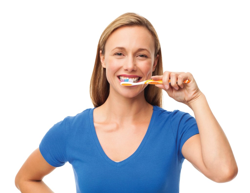 Woman checking her teeth while learning about gum recession causes.